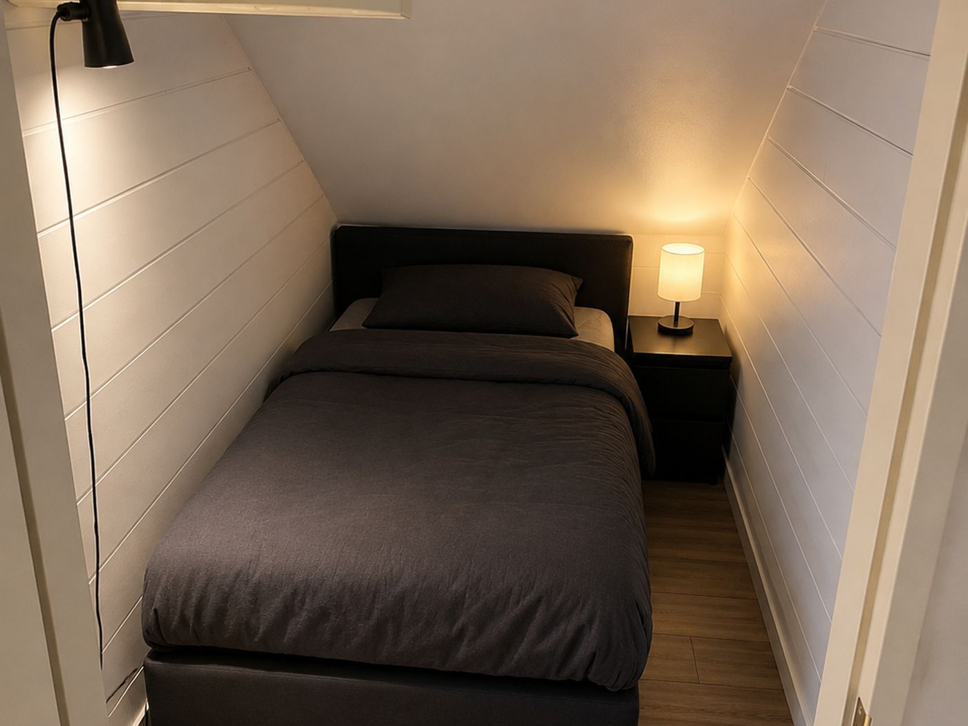 Ruhiges Einzelzimmer mit Bett, Nachttisch und Leselampe